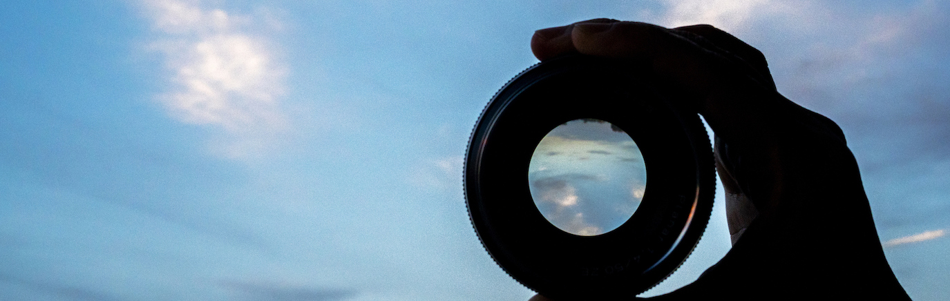 hand holding lens watching cloudscape